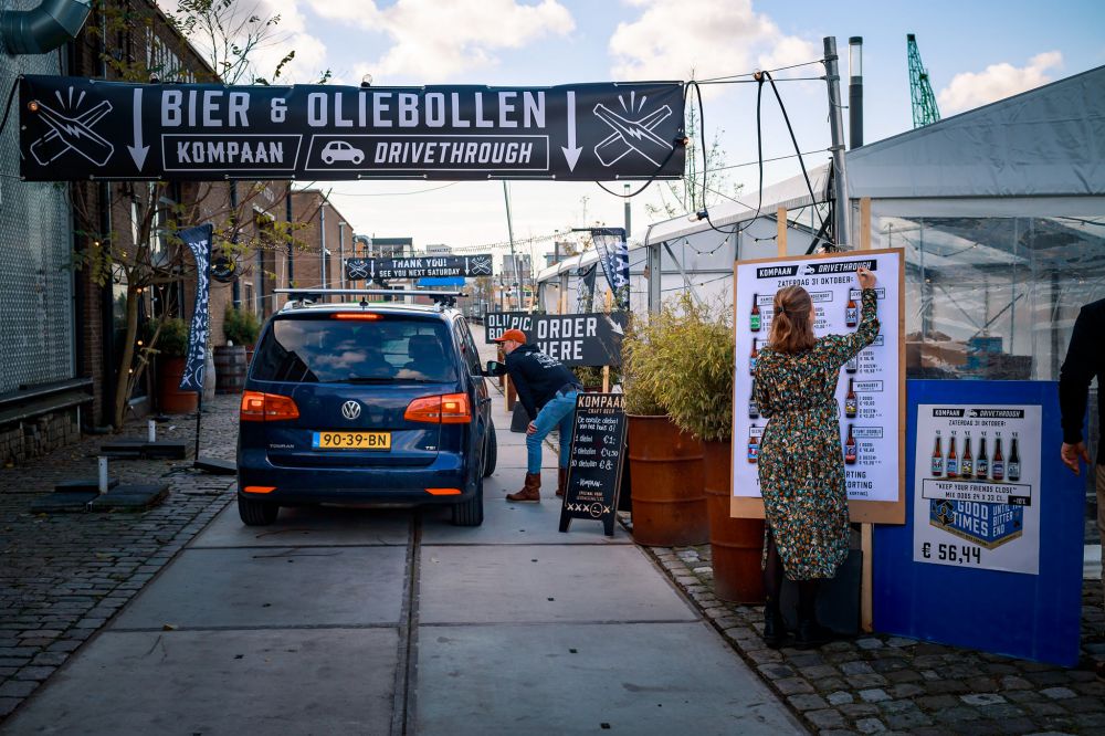 een drive threw waar een auto in staat en een man een bestelling opneemt